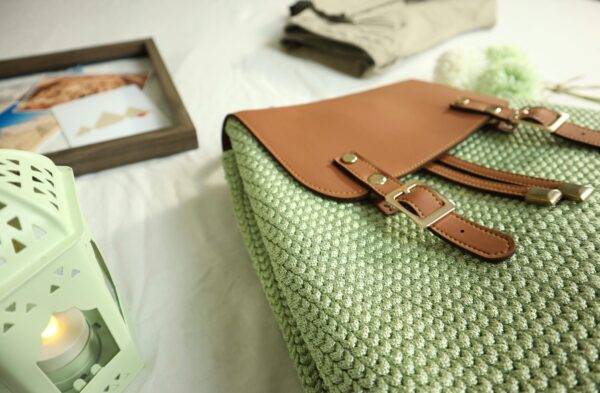 Close-up of a handcrafted crochet bag with leather accents, artistic home decor setting.